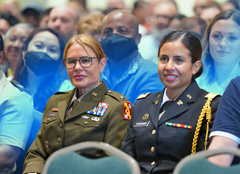 Two women in military uniform sitting in a crowd at an event
